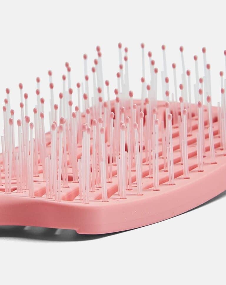 Close-up of a pink hairbrush with white bristles and rounded tips.